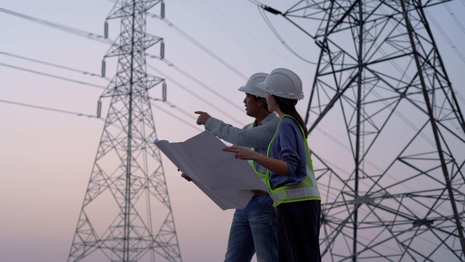 Two specialist electrical engineer working near to High voltage tower.